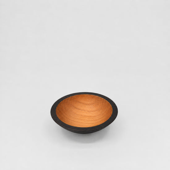 Wooden bowl with black rim on a light gray background