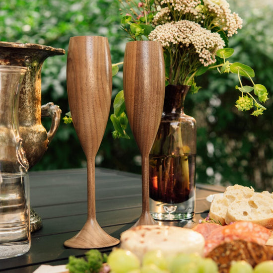 Outdoor setting with wooden goblets, bread, and fruit on a table.