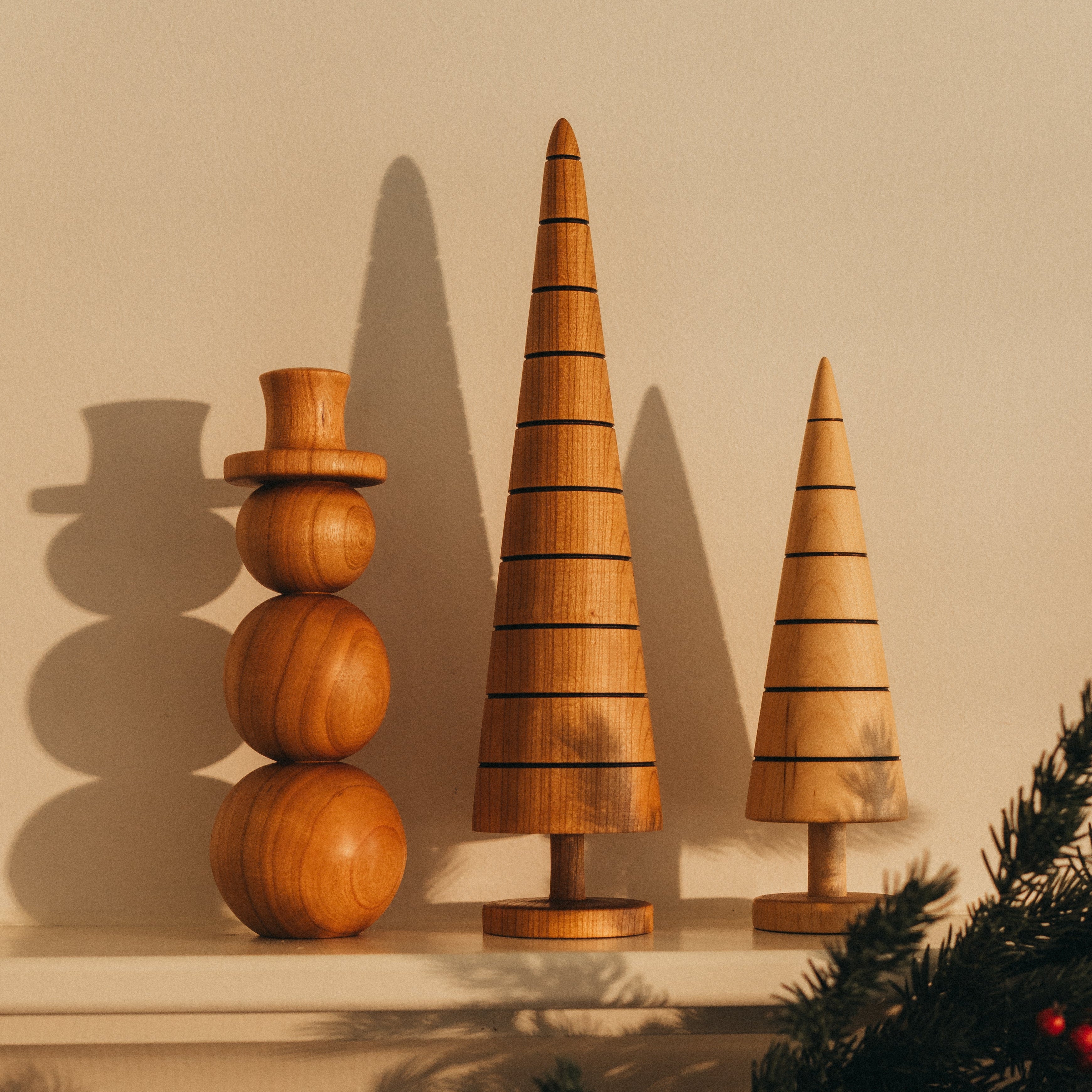 Wooden decorative trees and a snowman on a mantelpiece with Christmas garland