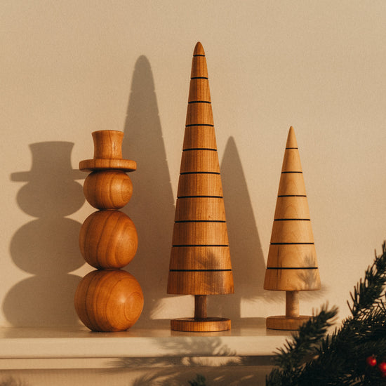 Wooden decorative trees and a snowman on a mantelpiece with Christmas garland