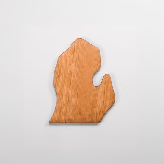 Wooden cutting board shaped like the state of Michigan on a light gray background
