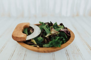 A 9-inch small chopping bowl set with Cherry bowl and mezzaluna knife. Shown with pre-chopped salad