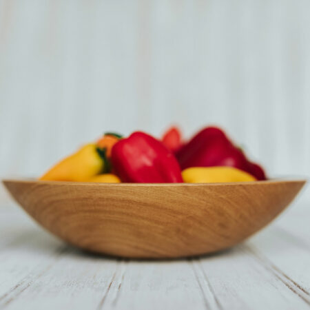 9-inch Beech large wooden snack bowl filled with tiny red and yellow peppers