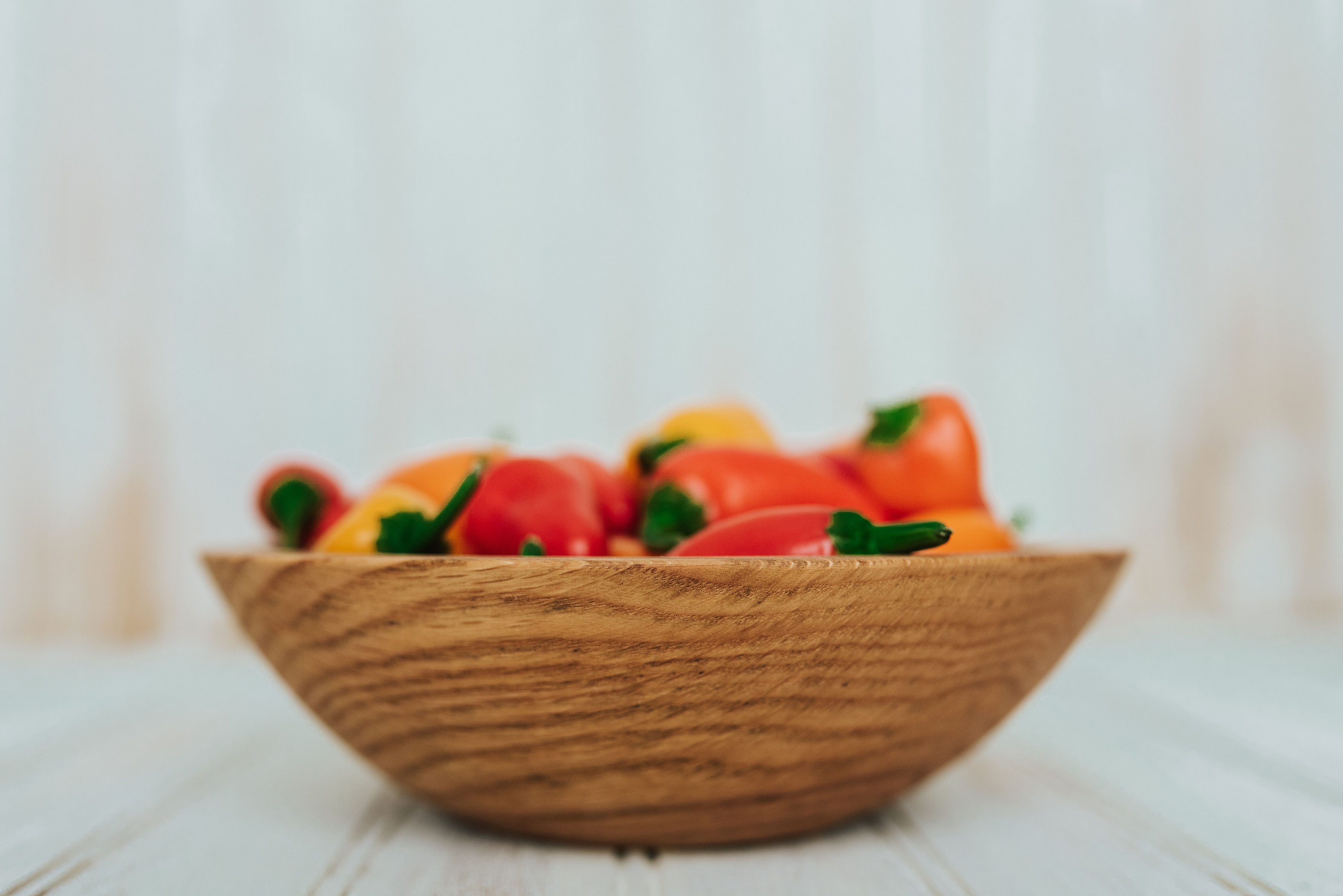 One of Holland Bowl Mill's durable wooden bowls holding some assorted peppers.