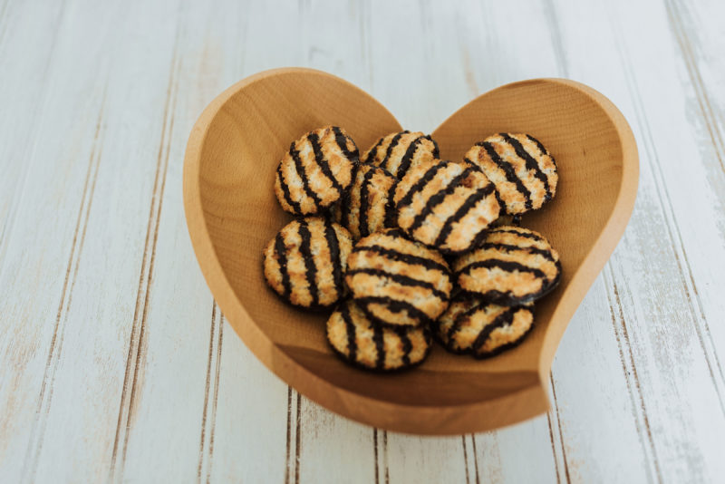 A tear drop bowl that is heart shaped, holding a macaroons.