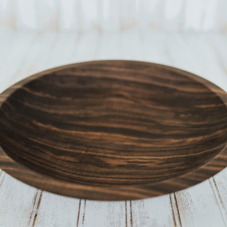 A shallow yet large wooden plate made from walnut.