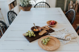 Wooden plates are just as durable as our bowls and boards. A wooden plate with grape son it next to a charcuterie board with cheese and crackers.