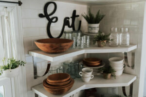 Wooden serving bowls stacked in a kitchen shelving unit.