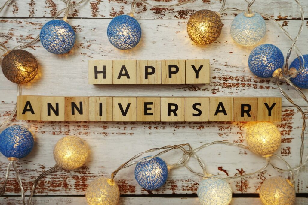 The 5th Year wedding anniversary gift is commonly made of wood. Happy Anniversary spelled out in wooden letter blocks adorned with blue and gold ornaments.