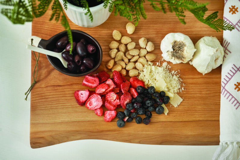 Fruits, nuts, and cheese sit atop a Holland Bowl Mill double live edge wood cutting board.