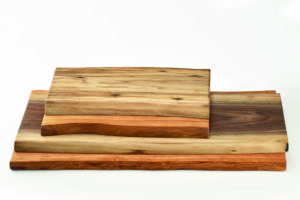 A small double live edge wood cutting board sits atop another. Known for their rustic style